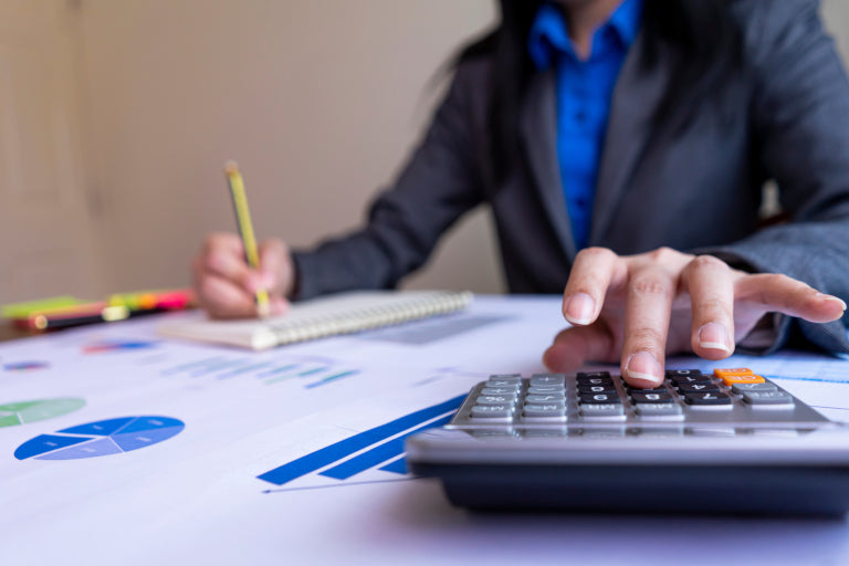Persoon aan het werk met rekenmachine en financiële grafieken