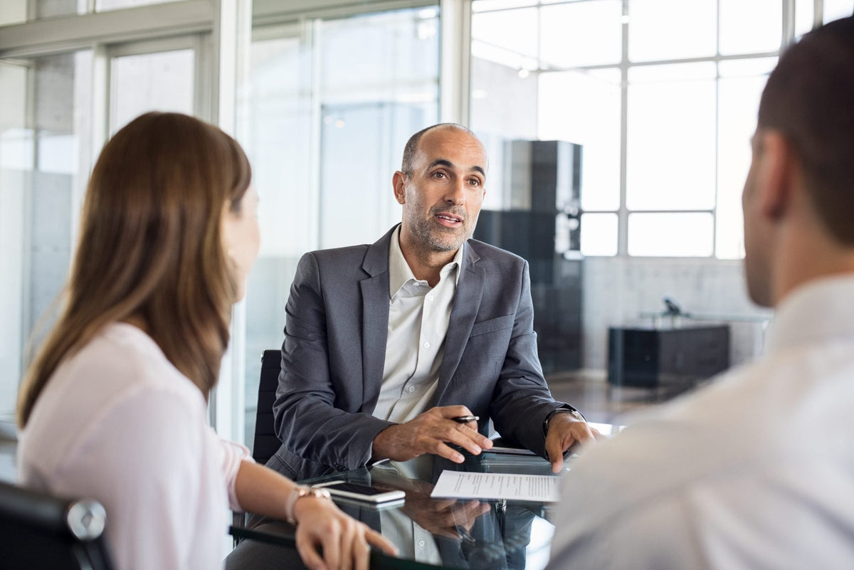 Consultant in gesprek met twee klanten aan een kantoortafel